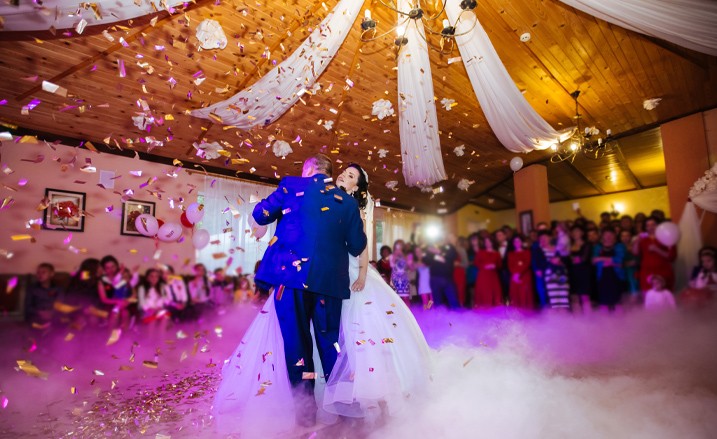 bride and groom having first dance with smoke and confetti