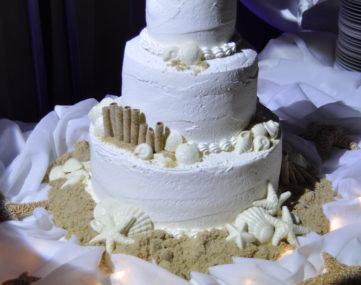 spotlight illumitates wedding cake with candle lights under silk