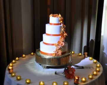 spotlight illumitates wedding cake ringed by tea light candles on table